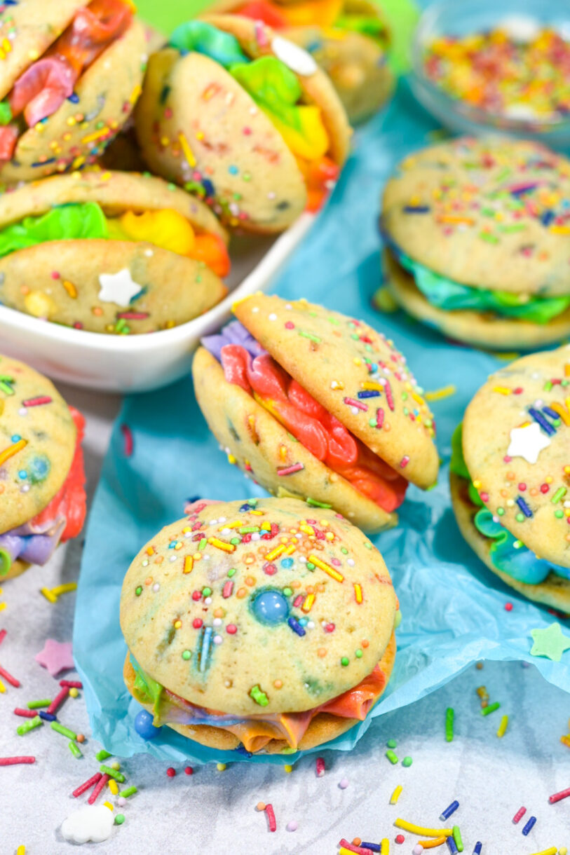 Mini whoopie pie treats arranged on a sheet of blue tissue paper, with rainbow sprinkles