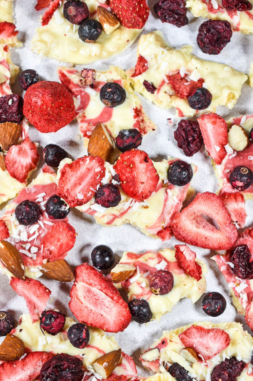 Closeup of pieces of white chocolate berry bark topped with almonds, freeze dried strawberries, and blueberries