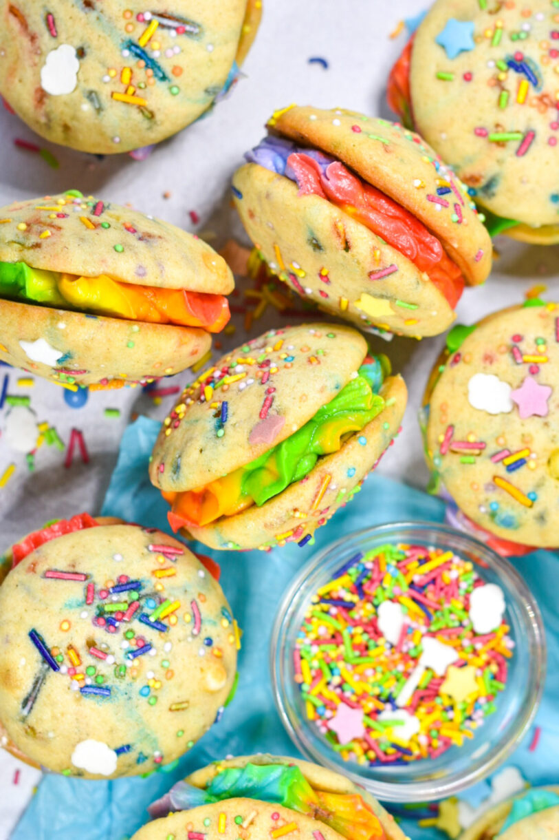 Miniature rainbow buttercream whoopie pies and a bowl of rainbow sprinkles