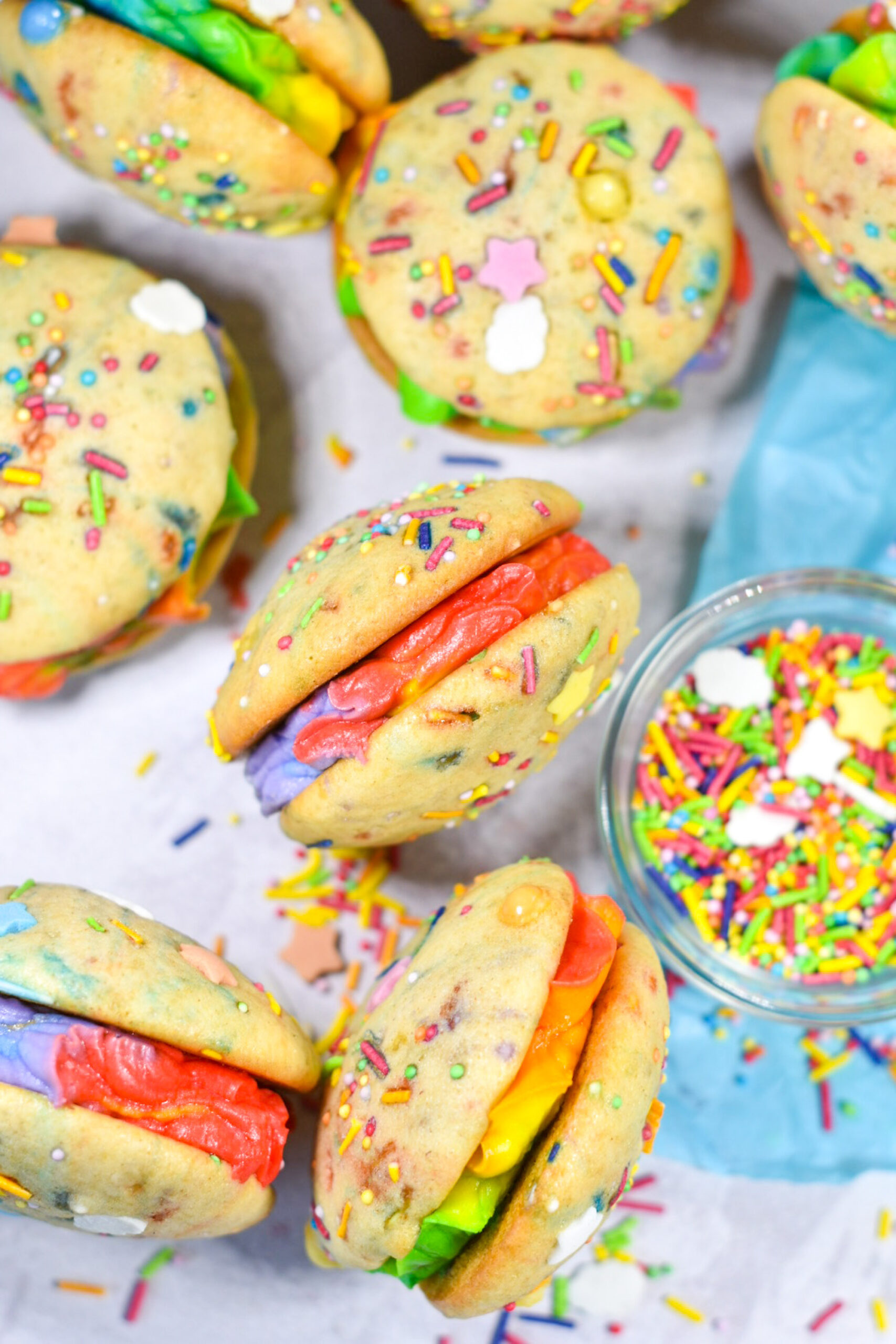 Mini buttercream rainbow whoopie pies and a bowl of rainbow sprinkles