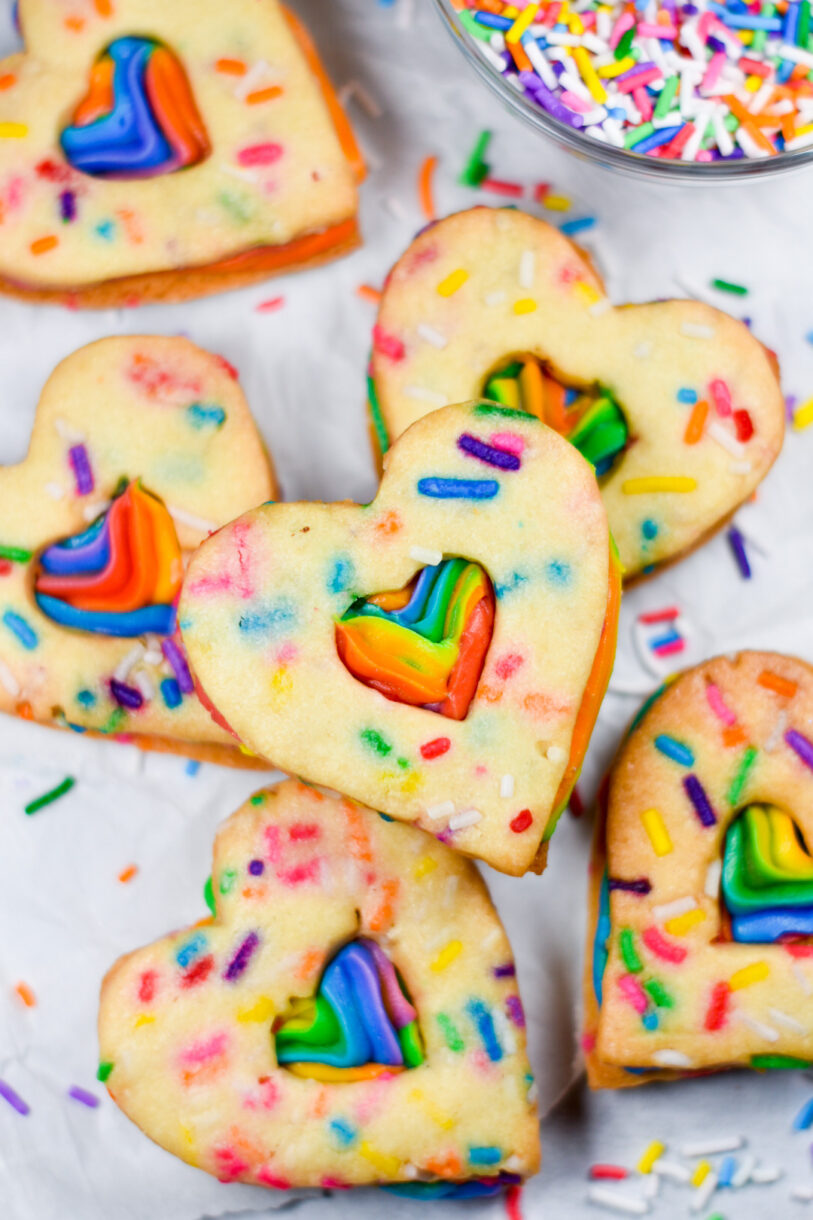 Rainbow Buttercream Cookies shaped like hearts, and a bowl of rainbow sprinkles