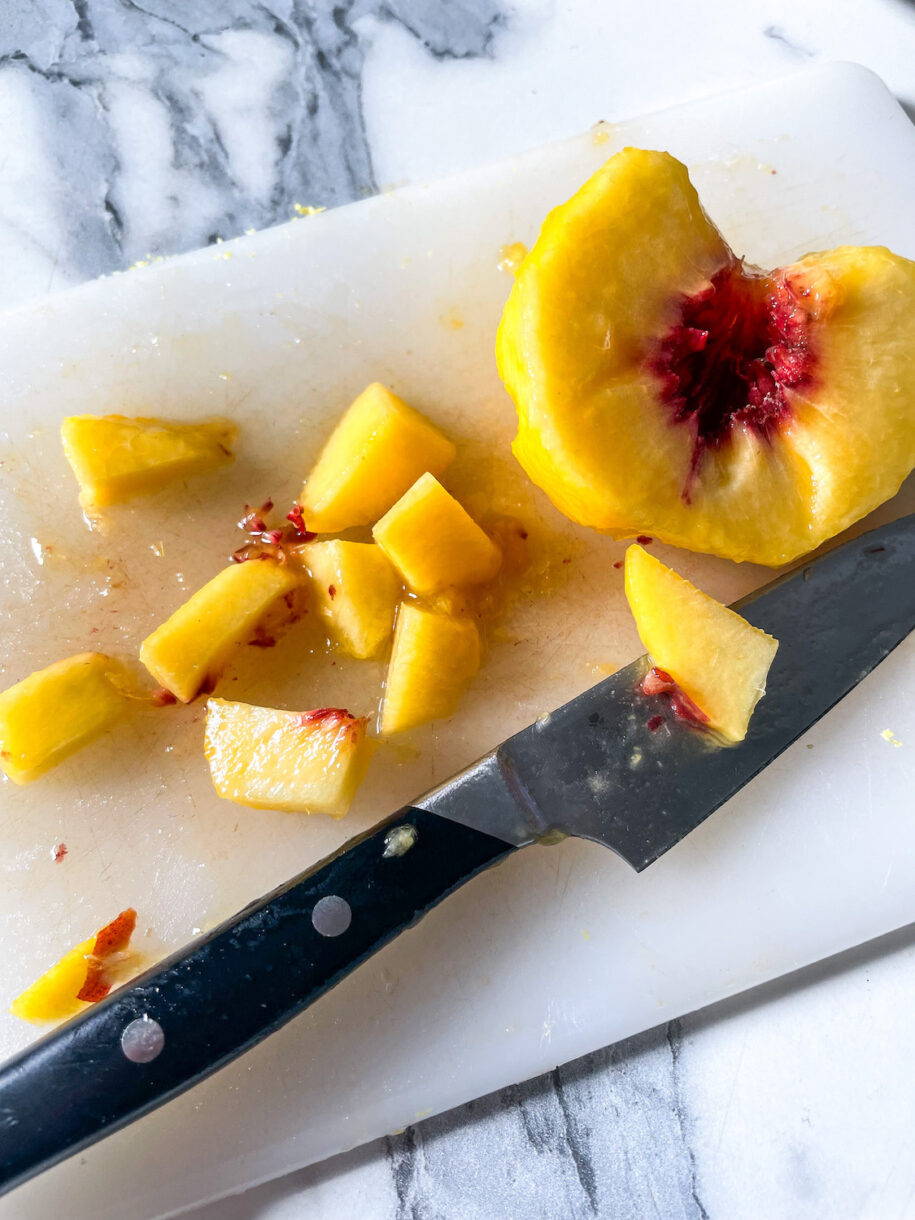 Diced peaches on a cutting board with knife