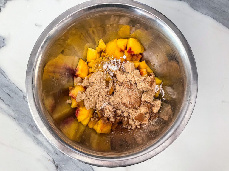 Diced peaches in a bowl with brown sugar and spices