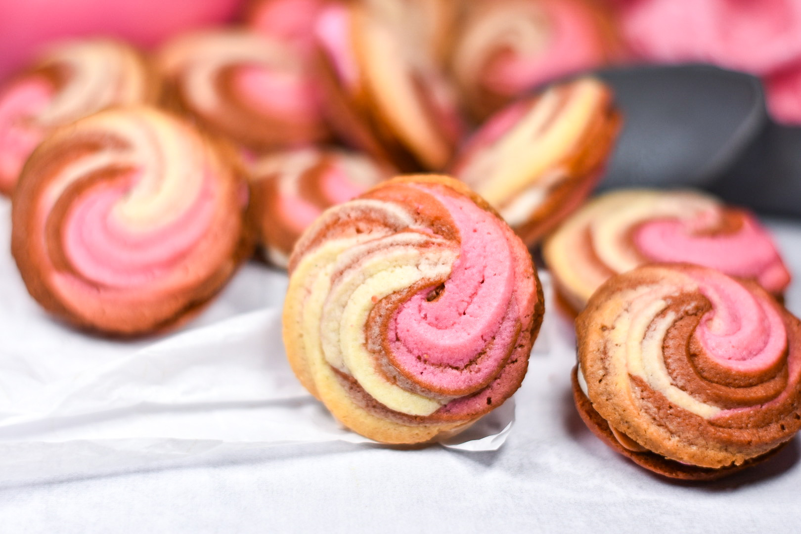 piped neapolitan butter cookies arranged on a sheet of white parchment