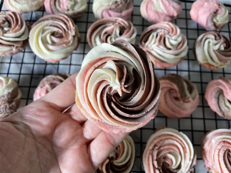 Hand holding cookie with swirls of buttercream