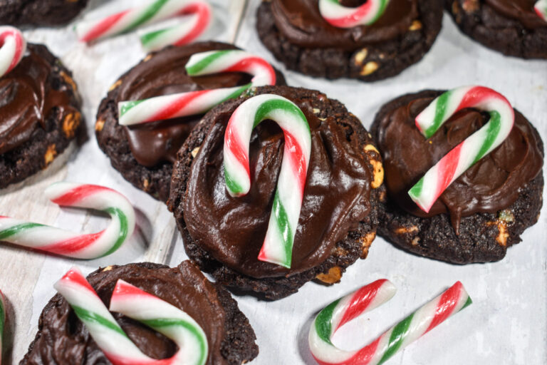 Chocolate peppermint candy cane cookies on a white surface, with miniature candy canes