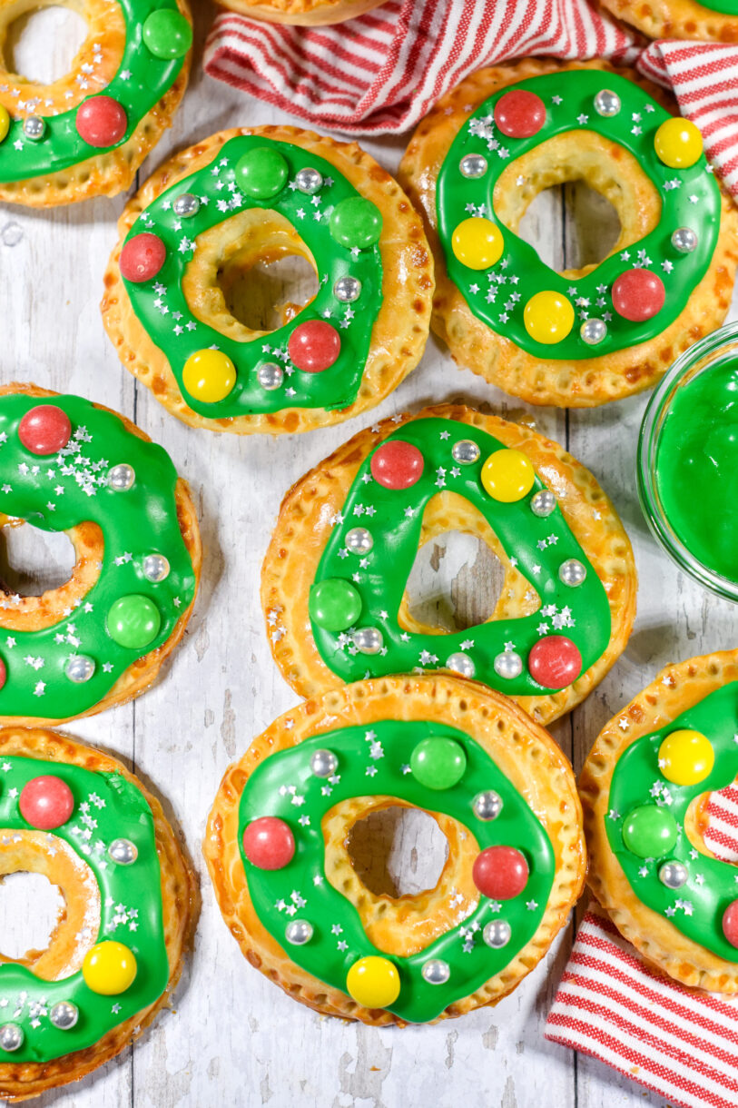 Photo of wreath shaped pastries with green frosting and candy decorations, on a white background