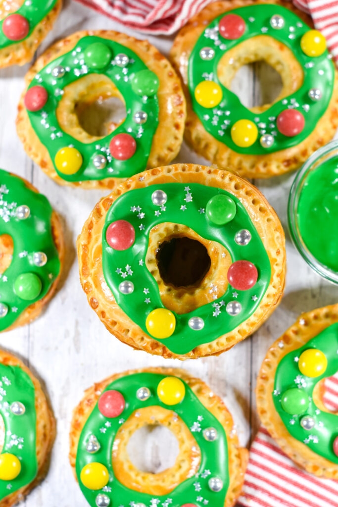 Wreath shaped hand pies with green glaze and candy decorations, on a white background