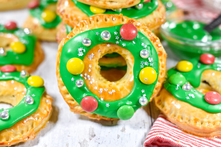 Wreath shaped hand pies with green glaze and candy decorations, on a white background