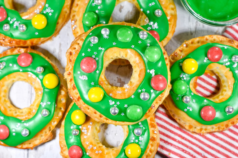 Photo of wreath shaped pastries with green frosting and candy decorations, on a white background