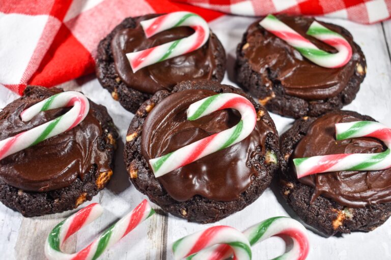 Dark chocolate mint cookies and mini candy canes on a white wooden surface