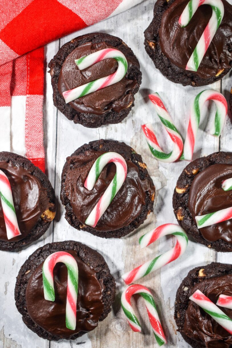 Dark chocolate peppermint cookies and mini candy canes on a white wooden surface