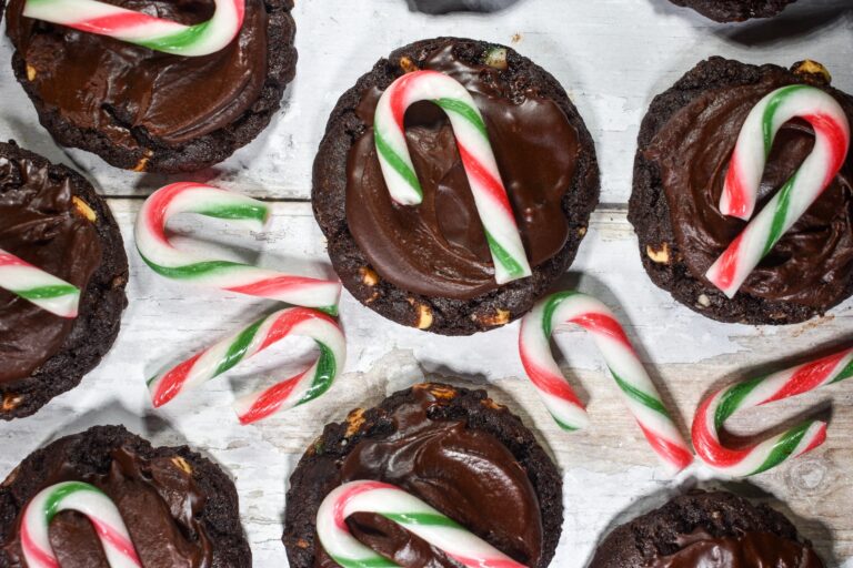 Dark chocolate mint cookies and mini candy canes on a white wooden surface