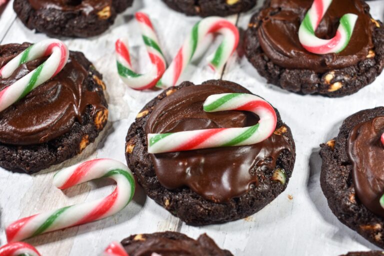 Chocolate peppermint cookies and mini candy canes on a white wooden surface