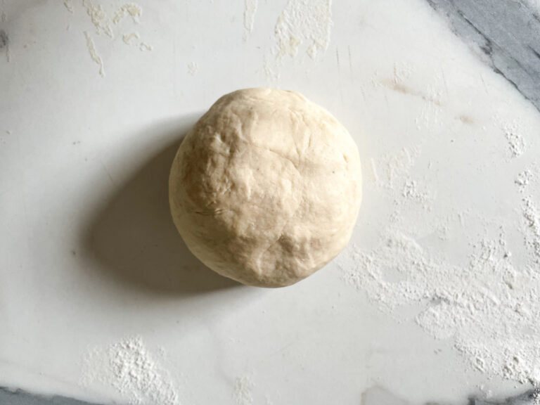Ball of pizza dough on marble countertop