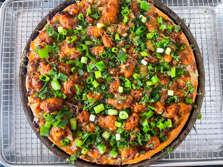 Buffalo cauliflower pizza garnished with parsley and spring onions