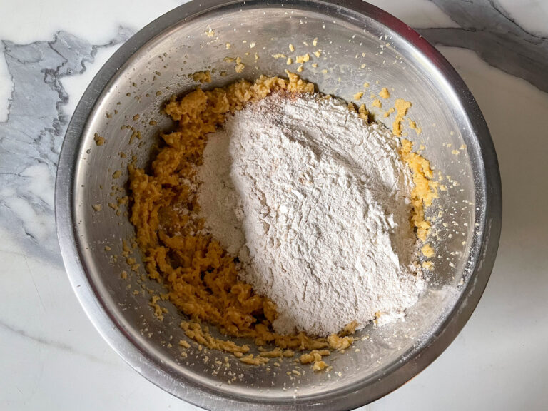 Metal bowl with whipped butter, sugar, and dry ingredients, before mixing