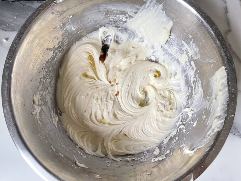 Bowl of cream cheese frosting with drops of vanilla bean paste