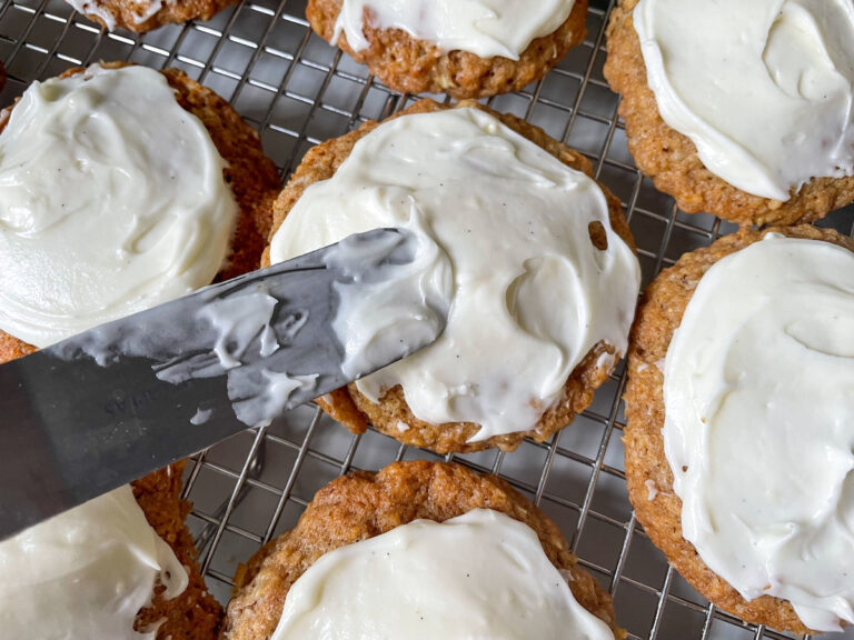 Small palette knife spreading cream cheese frosting on a cookie