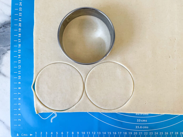 Three discs of shortcrust pastry on a blue rolling mat