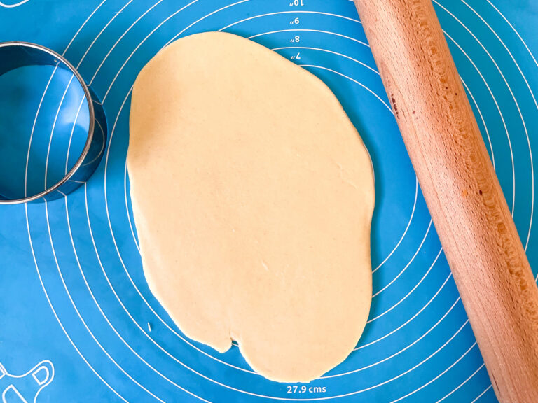 A blue silicone rolling mat, rolling pin, ring cutter, and shortcrust pastry