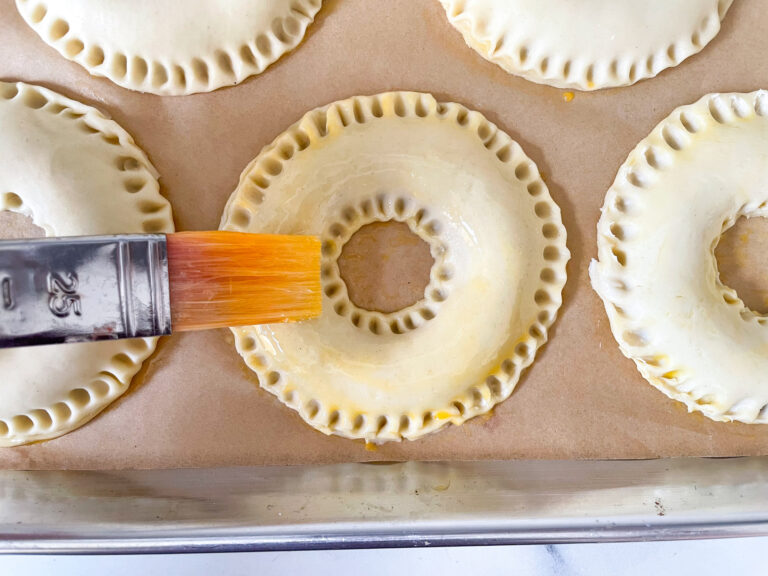 Closeup of pastry brush applying egg wash to a pastry