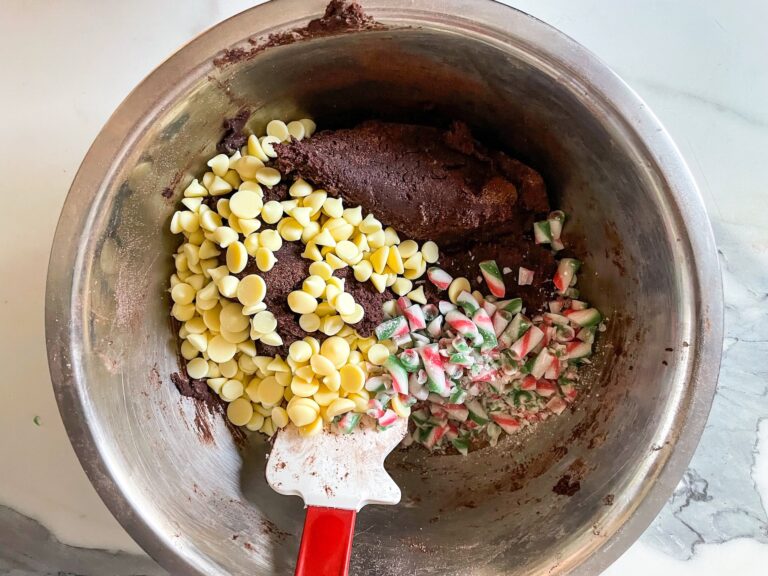 Chocolate cookie dough in bowl with white chocolate chips and crushed candy canes
