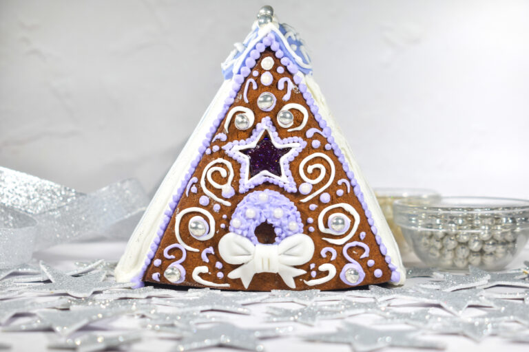 A-frame gingerbread house with white and purple decorations