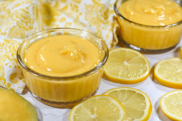 Lemon curd in a dish surrounded by fresh lemons