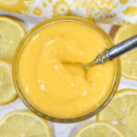 Lemon curd in a dish with lemons and a tea towel