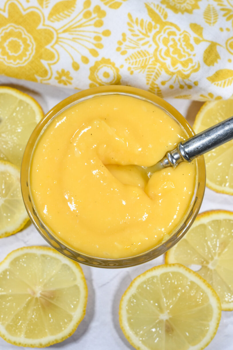 a bowl of lemon curd surrounded by slices of lemon