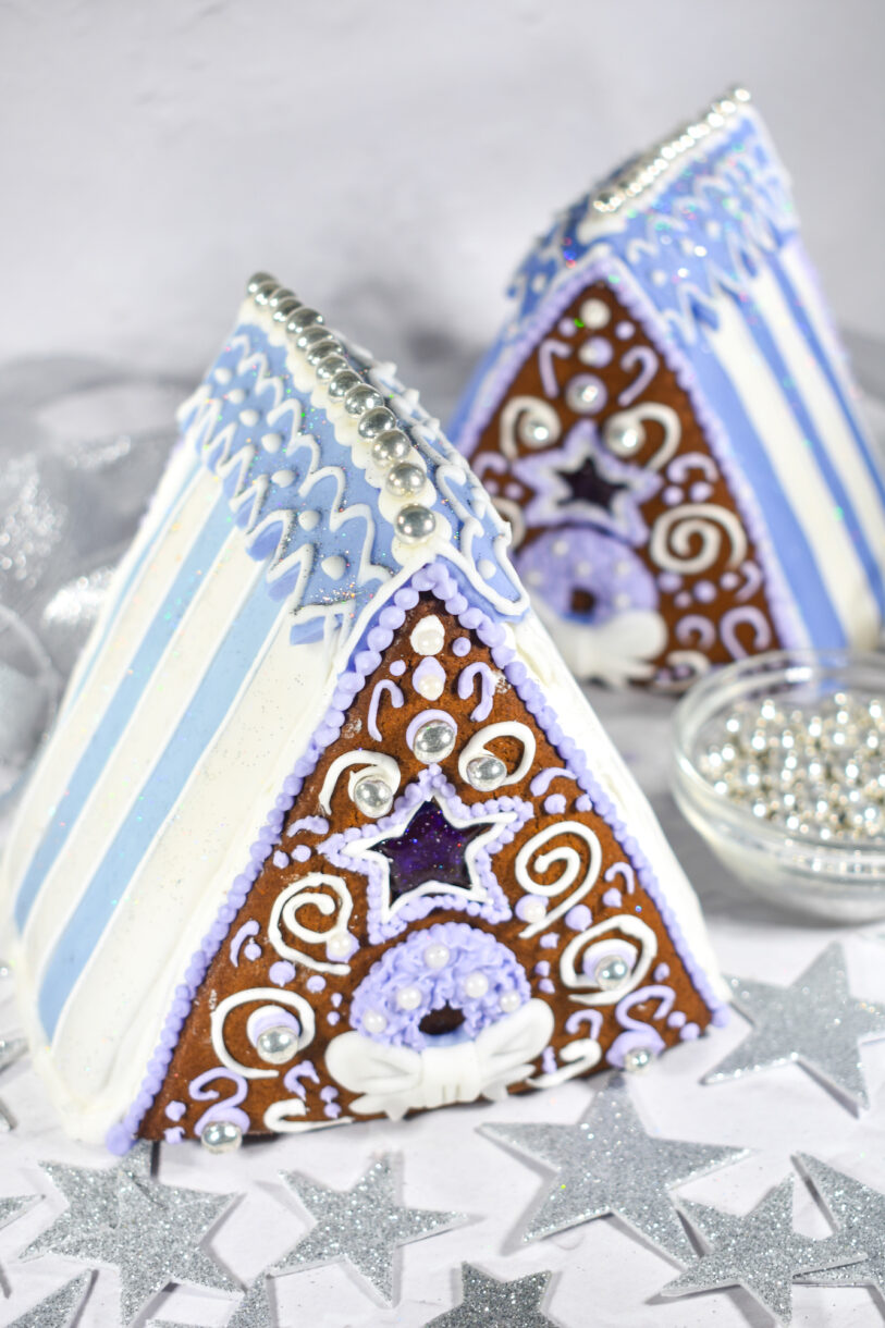 Two gingerbread houses and silver stars on white surface