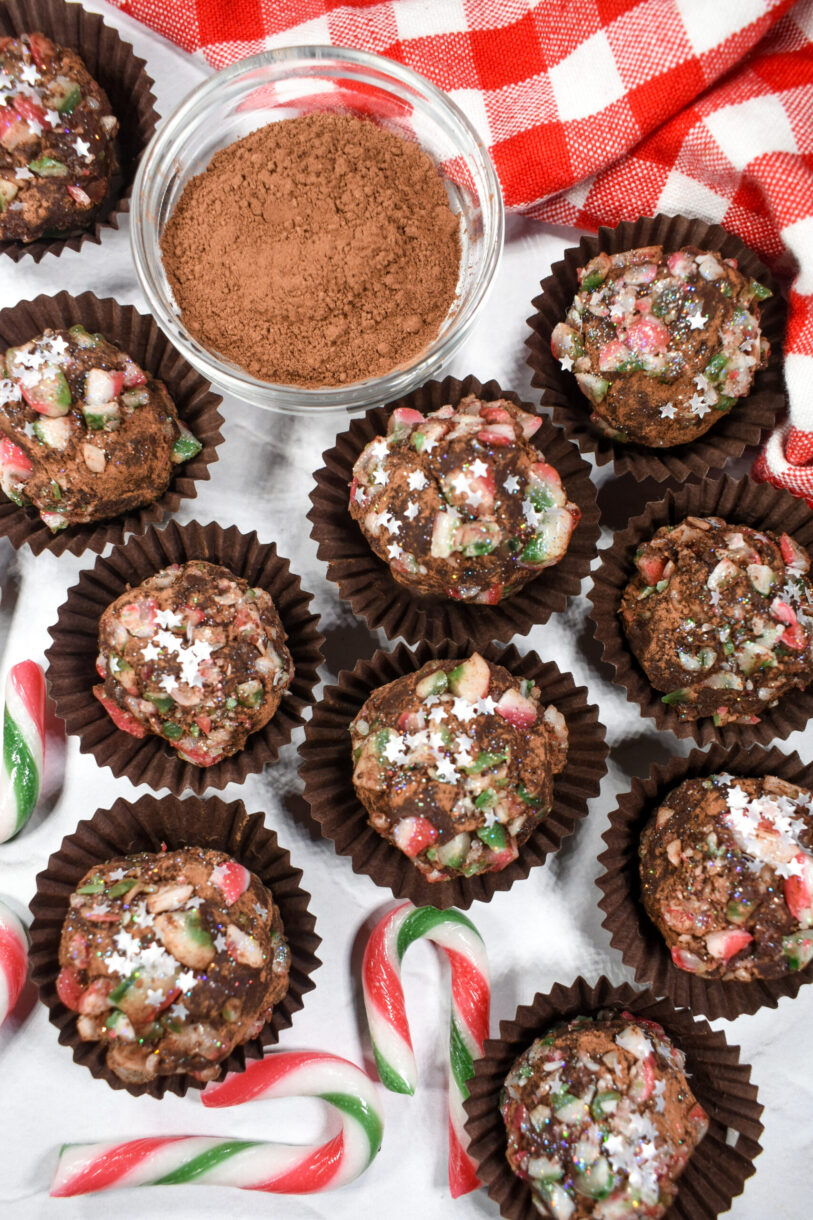 Candy cane chocolate truffles and crushed candy canes on white surface