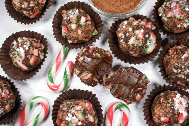 Candy cane Christmas truffles and crushed candy canes on white surface