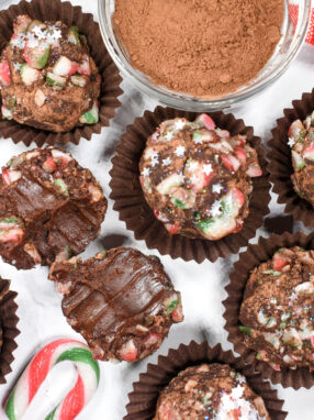 Candy cane chocolate truffles and crushed candy canes on white surface