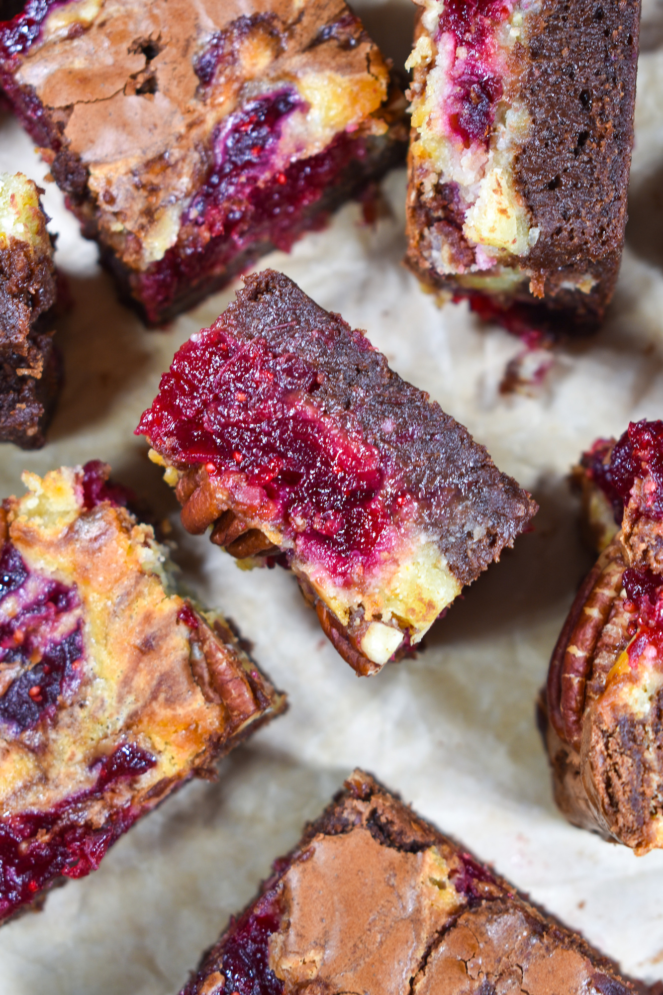 brie and cranberry brownies arranged on a sheet of baking parchment