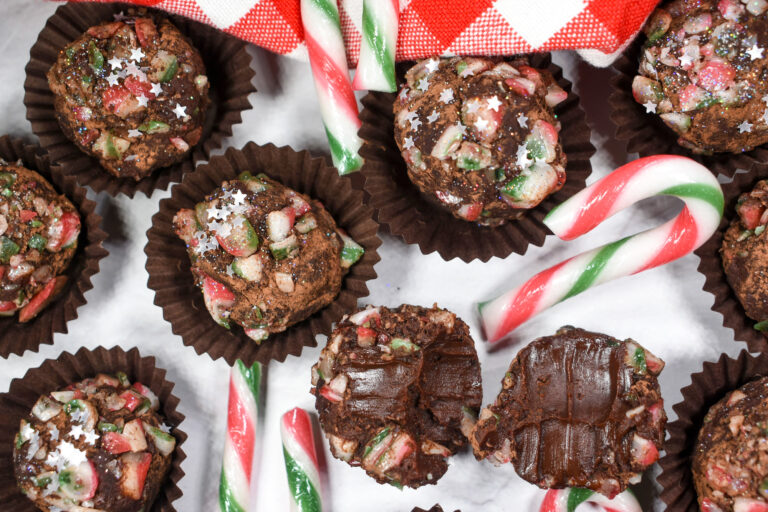 Candy cane chocolate truffles and crushed candy canes on white surface