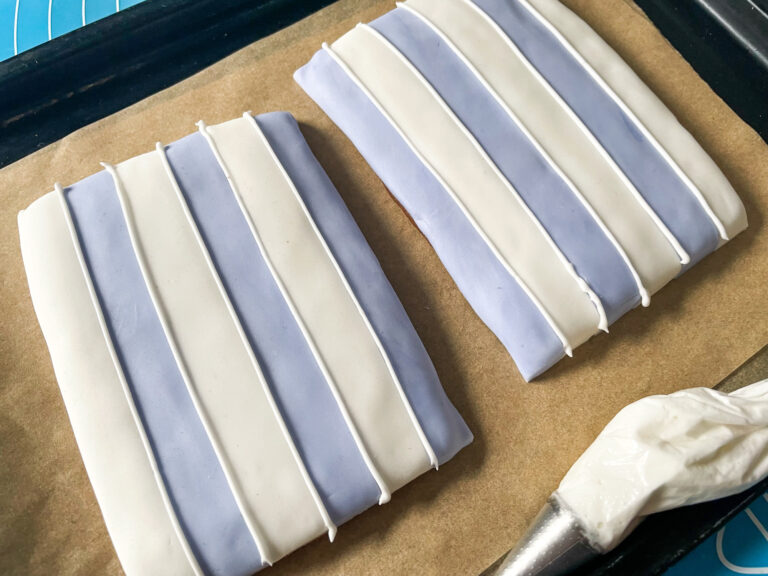 Purple and white striped fondant pieces on a sheet of parchment