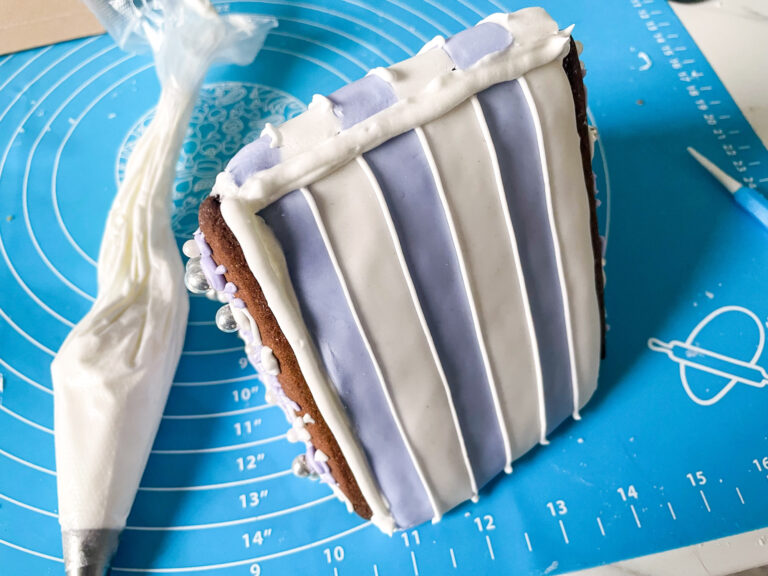 Gingerbread house and piping bag on blue silicone mat