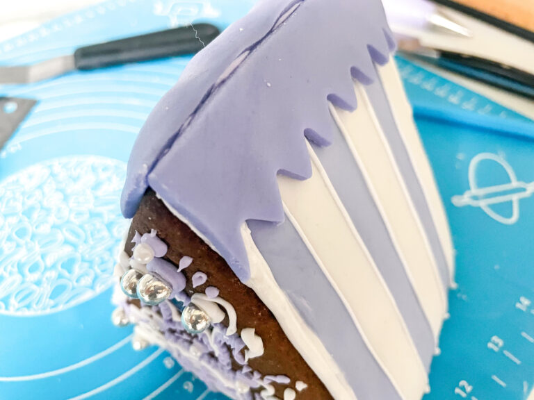 Covering the gingerbread house with purple and white fondant