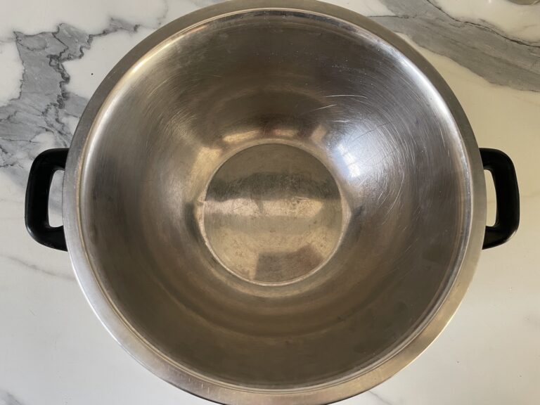 Metal bowl sitting on top of metal saucepan on countertop