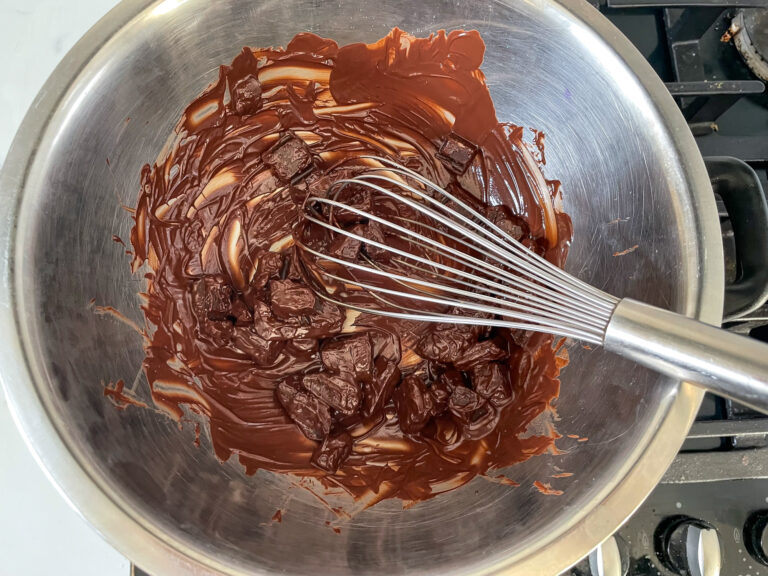 Whisk and melted chocolate in metal bowl