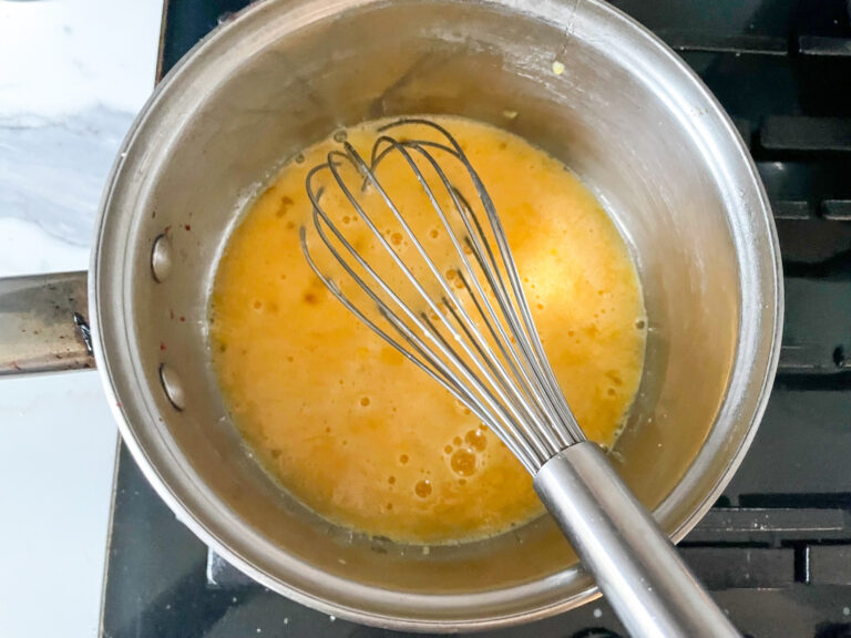 Whisking lemon curd ingredients in a saucepan