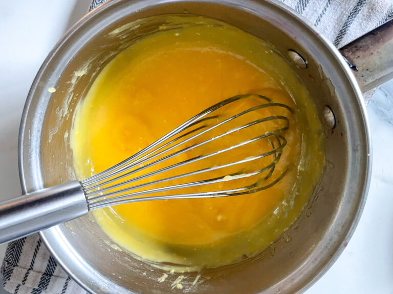 Lemon curd and whisk in a saucepan