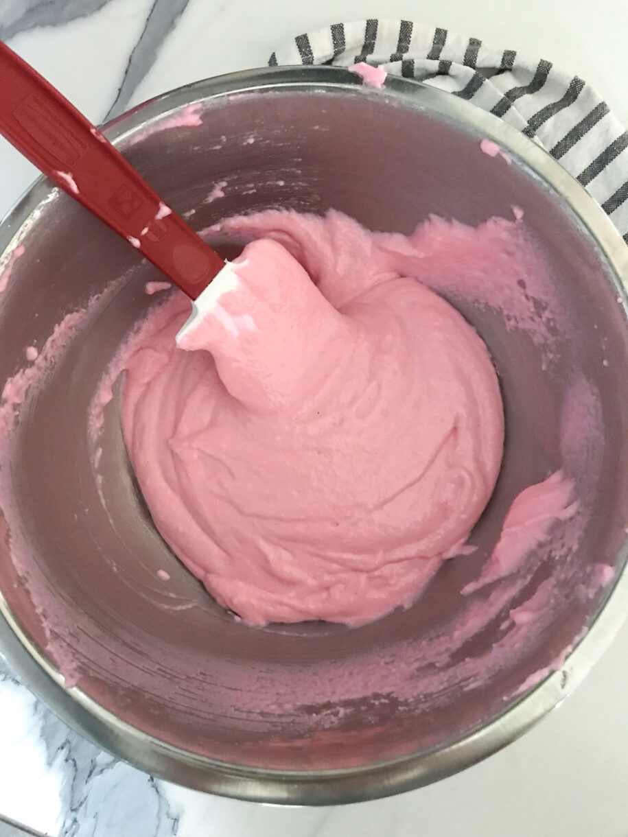 Bowl with pink macaron batter and a spatula