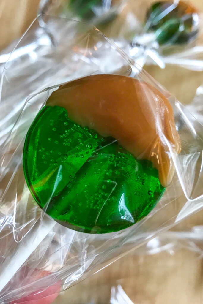 A green candy apple lollipop dipped in caramel