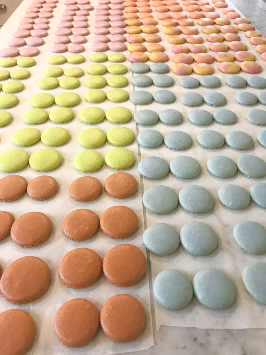 Macaron shells in rows on a marble countertop