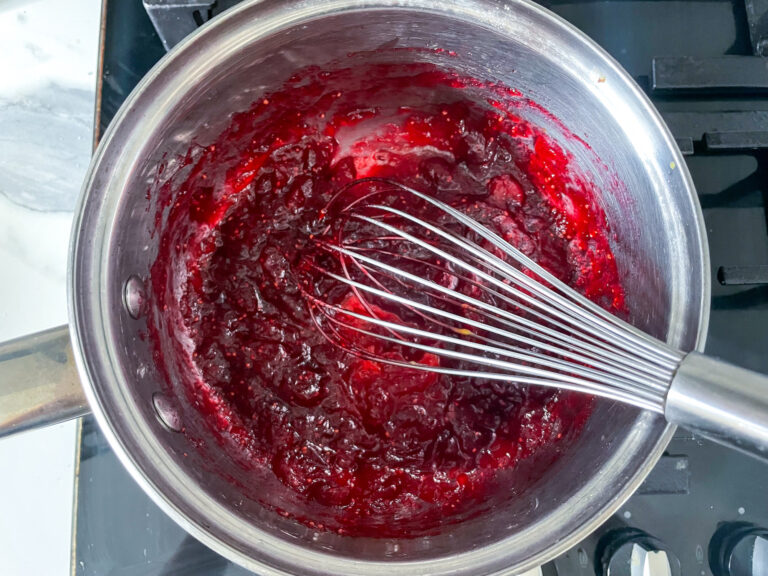 Cranberry compote in saucepan with whisk