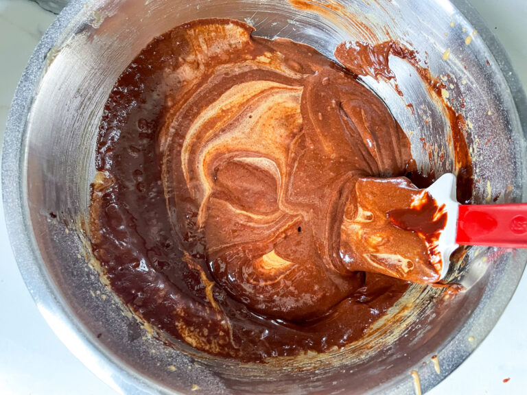 Adding chocolate mixture to batter in metal bowl