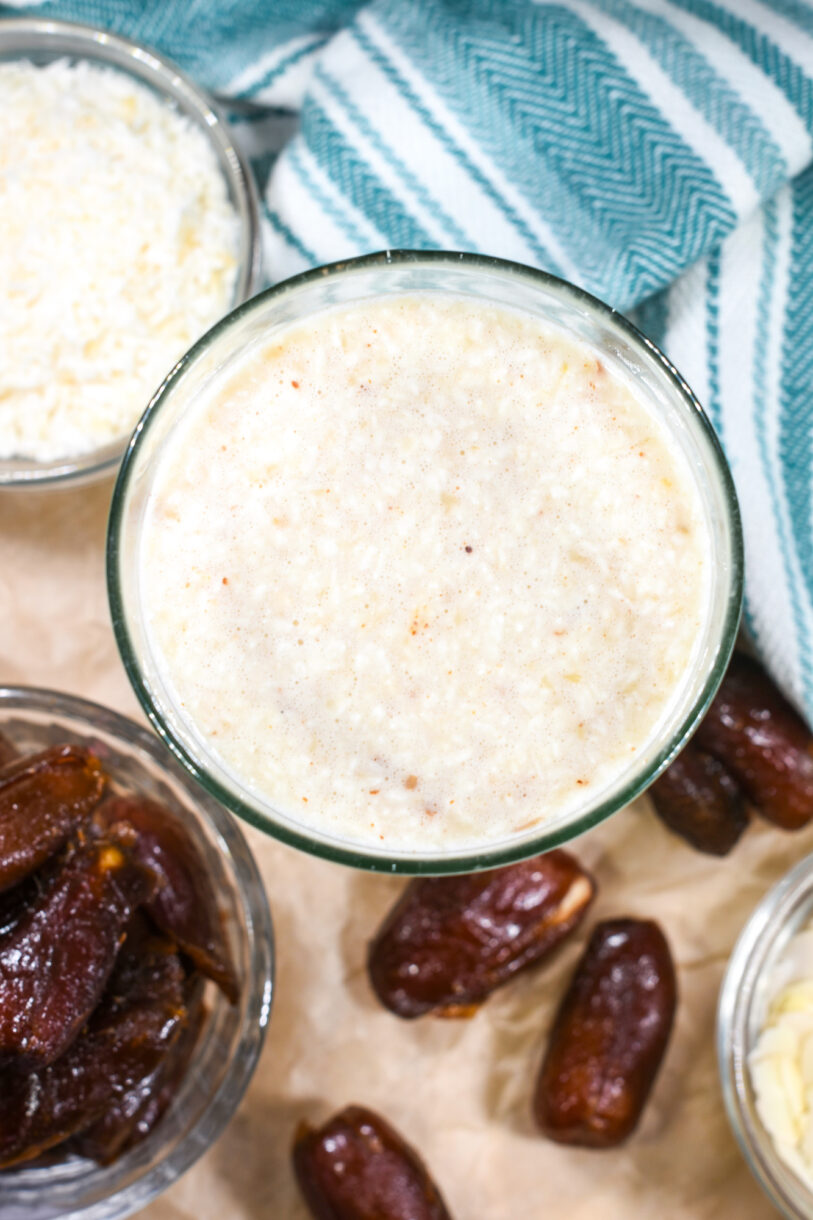 Almond and date smoothie with a bowl of coconut, dates, and a tea towel